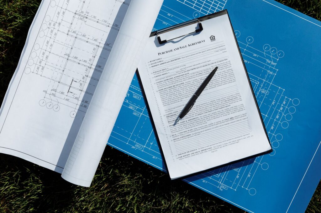 Mână care semnează un contract imobiliar cu stiloul, pe un birou, lângă un set de chei
