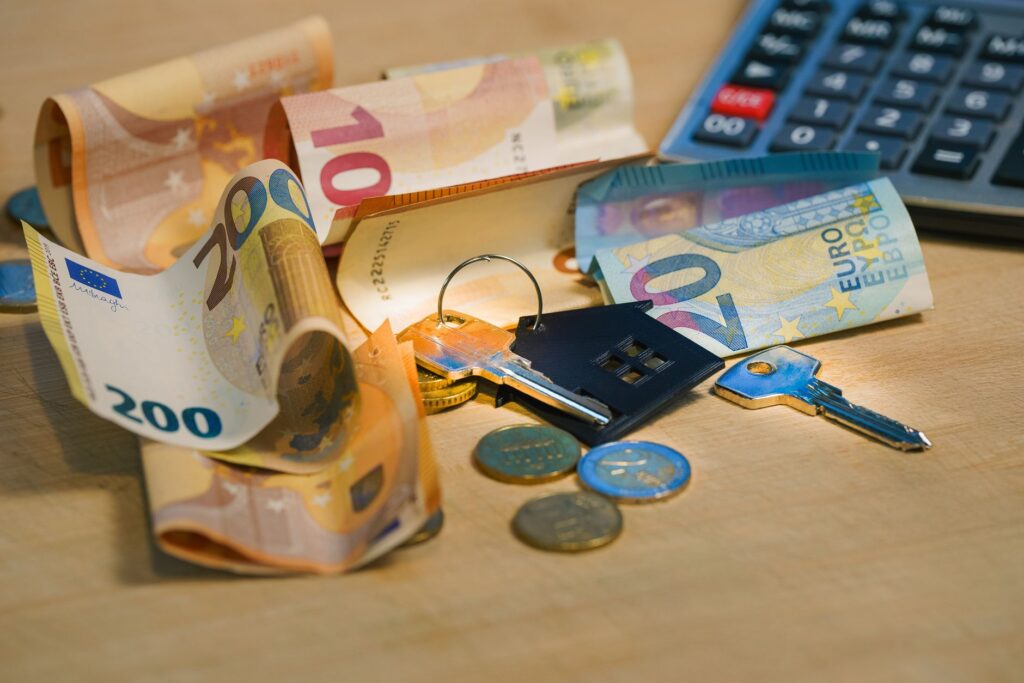 Randamentul brut și net al unei locuințe date în chirie Calculator, un set de chei și un carnet cu calcule pe o masă, alături de un contract de închiriere