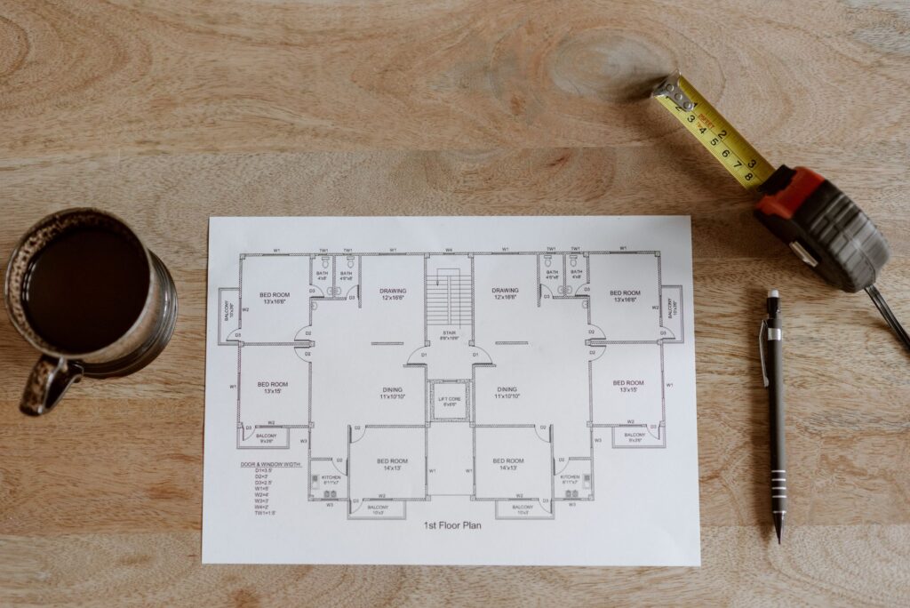 Plan de apartament tipărit, cu o ruletă de măsurat și un creion așezate deasupra